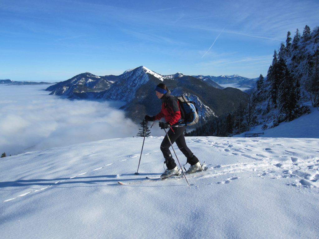 Eine Frau quert eine schneebedeckte Fläche mit Ski.